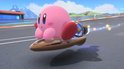 Kirby op een bruin hoverboard met straalmotor, vliegend op een racecircuit.