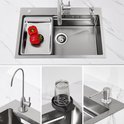 RVS spoelbak met rode pepers in een bakje, een kraan, een extra waterkraan, een glasreiniger en een zeepdispenser.
