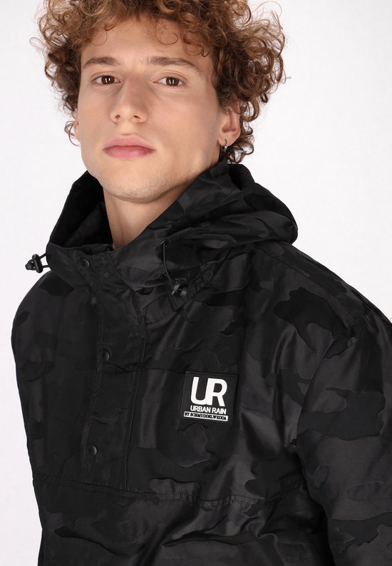 Detailopname van een zwarte camouflage jas met capuchon, voorzien van een 'UR URBAN RAIN BY SCHMUDDELWEDDA' logolabel.
