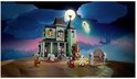 Une maison hantée la nuit avec une pleine lune, et des figurines de zombie, vampire, fantôme et loup-garou.