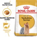 Gouden zak hondenvoer met rode opdruk 'ROYAL CANIN'. Een Yorkshire Terriër met rode strik in zijn haar staat afgebeeld.