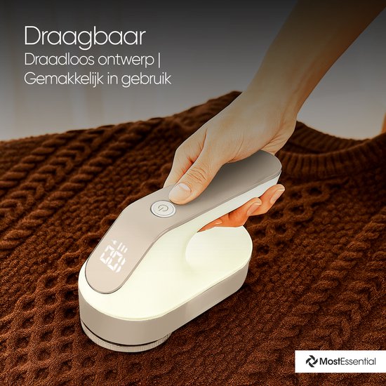 Hand houdt draadloze beige pluizenverwijderaar op bruin gebreid kledingstuk.