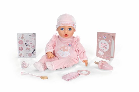 Baby pop in een roze pyjama met schaapapplicatie, muts, speen, flesje, bestek en boekje.