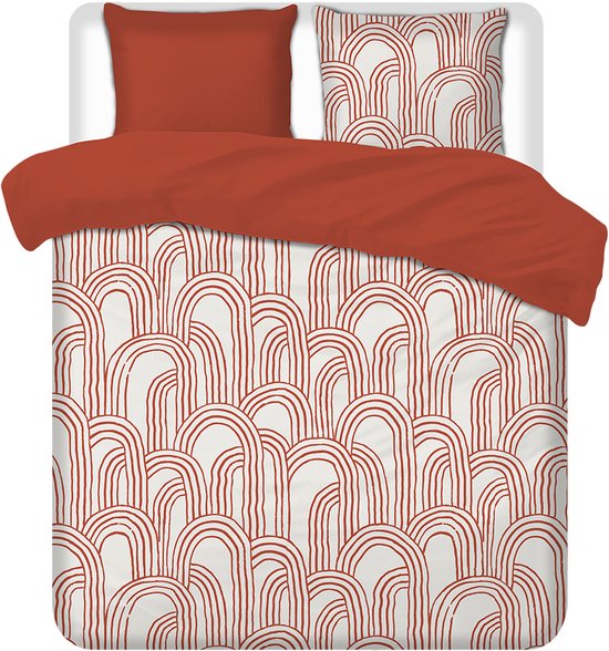 Bed met oranje plaid en crème dekbedovertrek met oranje gebogen lijnen patroon.