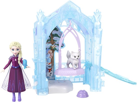 Elsa-pop met paarse jurk en laarzen, naast een ijzig blauw kasteel met een witte vos op een schommel, een sneeuwpop en ijsberen. Glijbaan aanwezig.