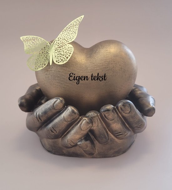 Antiek gouden hart in handen, met delicate vlinder en tekst 'Eigen tekst'.