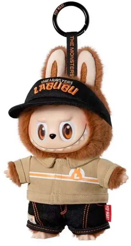 Bruine Labubu knuffel met zwarte pet met 'The Monsters Labubu' tekst, beige jasje met oranje strepen en denim short.