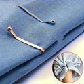 Zilveren en roségouden brocheclips op blauw textiel, met een detail van een kledingstuk dat wordt vastgeklemd.
