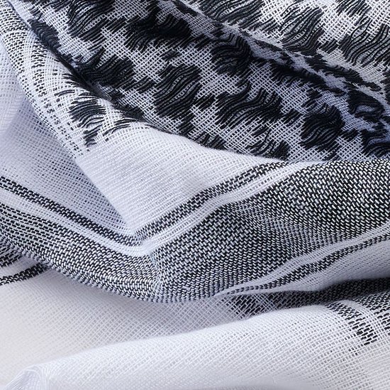 Detail van zwart-witte stof met traditioneel patroon en gestreepte rand.