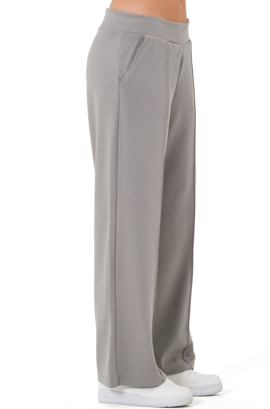 Zijkant van een grijze joggingbroek met rechte pijp, gedragen door een model.