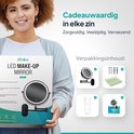 Vrouw met krullend haar die de verpakking van een Mirlux led make-up spiegel vasthoudt.