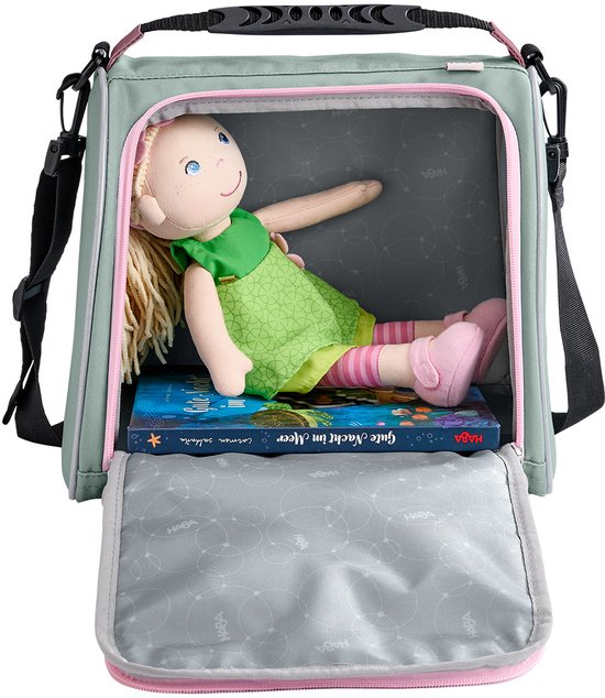 Groene tas met roze randen, open met een pop en boek erin.
