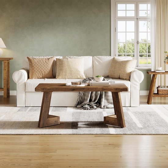 Bruine houten salontafel met verweerd oppervlak, in een woonkamer met een bank en een open haard.