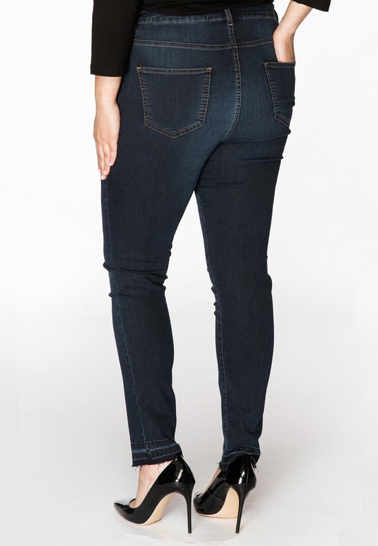 Model van achteren met donkerblauwe spijkerbroek met hoge taille, zwart shirt en zwarte hakken.
