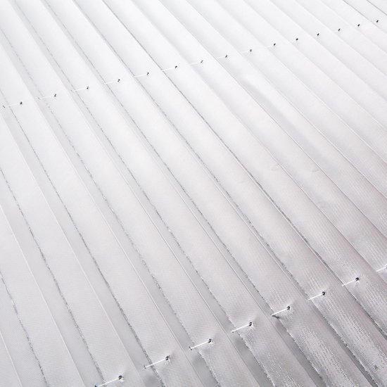 Detailopname van de witte, gevouwen stof van het zonnescherm met kleine gaatjes.