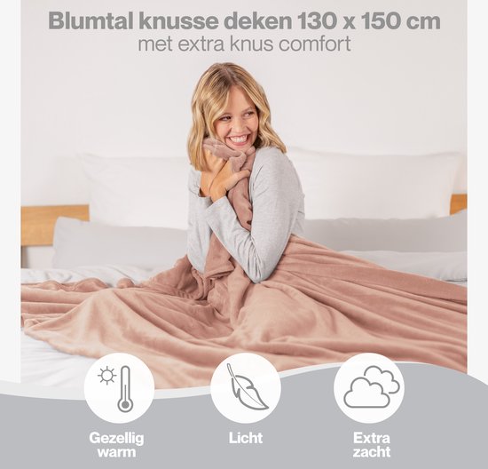 Een vrouw omhelst een oud roze Blumtal fleecedeken van 130x150 cm op een bed.