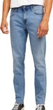 Man met een witte t-shirt en blauwe jeans. De focus ligt op de jeans met knopen.