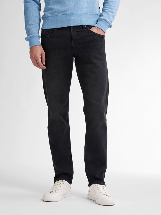 Model in zwarte, rechte jeans met lierblauwe sweater met ronde hals.