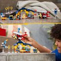 Iemand speelt met de LEGO Sonic Tails' werkplaats en het Tornado-vliegtuig op een grijze tafel.