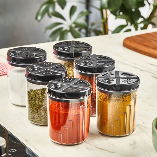 Ensemble de 6 pots à épices transparents avec couvercles noirs, remplis d'épices telles que le paprika, le curcuma et les herbes.