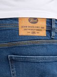 Detail van de achterkant van een spijkerbroek met een bruin leren label met de tekst 'Petrol Industries Denim Driven Since 1989'.