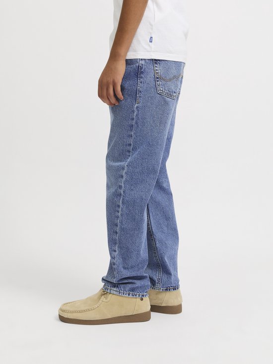 Zijaanzicht van een jongen in een lichtblauwe spijkerbroek en beige suède schoenen.