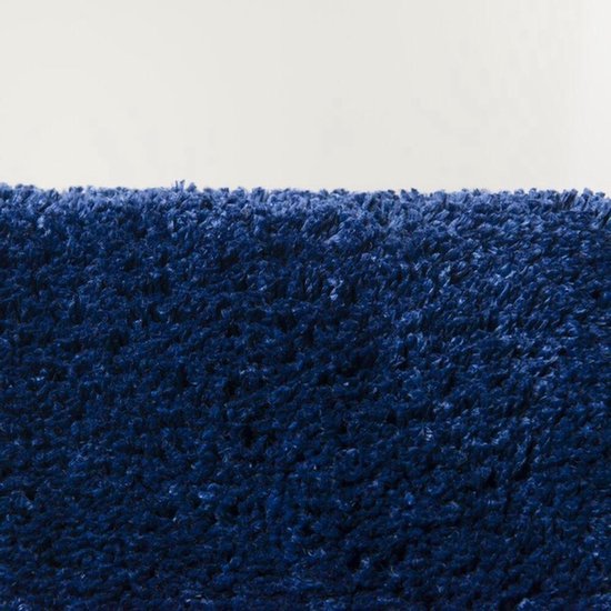 Close-up van een donkerblauwe, shaggy badmat met een pluizige textuur.