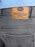 Close-up van de bruine leren Petrol Industries patch op de achterkant van een grijze jeans.