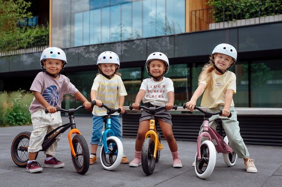 Vier kinderen met helmen staan met hun fietsen klaar.