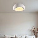 Wit plafondlamp met steeneffect, bolvormig met een opening aan de voorkant. Boven een bank.