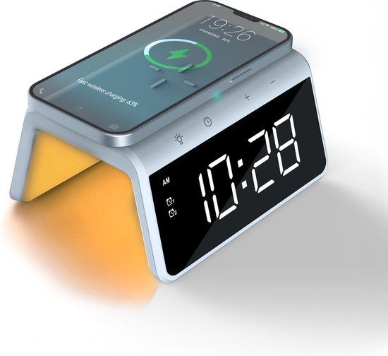 Witte wekker met digitale tijd 10:28 en een smartphone die draadloos oplaadt.