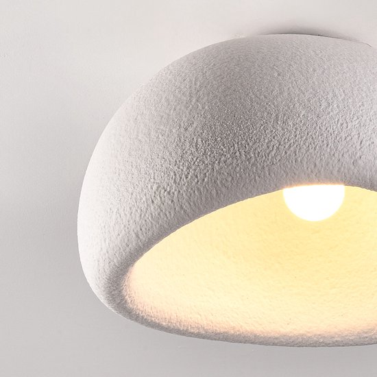 Close-up van de witte plafondlamp met steeneffect en een gloeiende lamp erin.