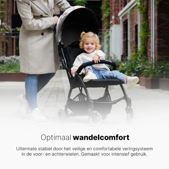 Een vrouw duwt een zwarte buggy met kind op straat.