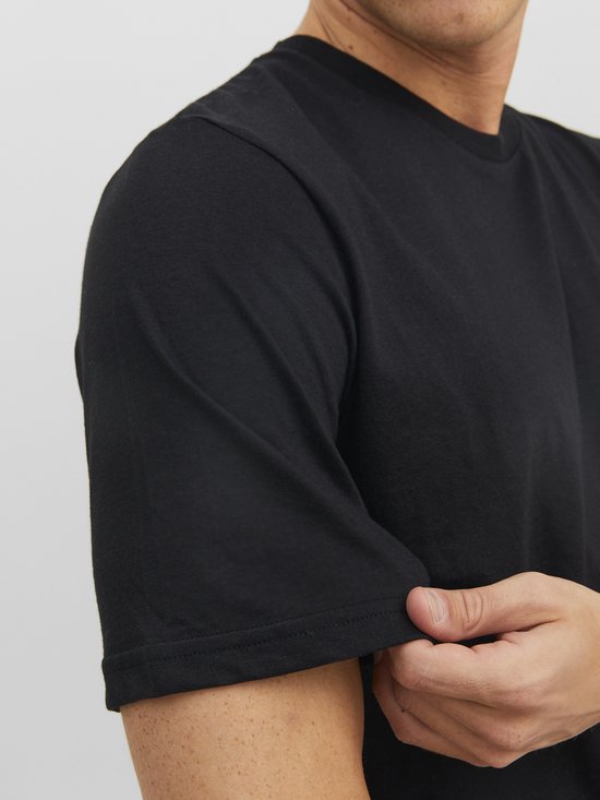 Een man trekt aan de zoom van een zwart T-shirt.