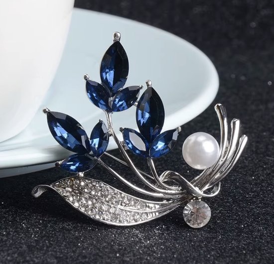 Zilverkleurige broche met blauwe kristallen bladeren, parel en strass steentjes.