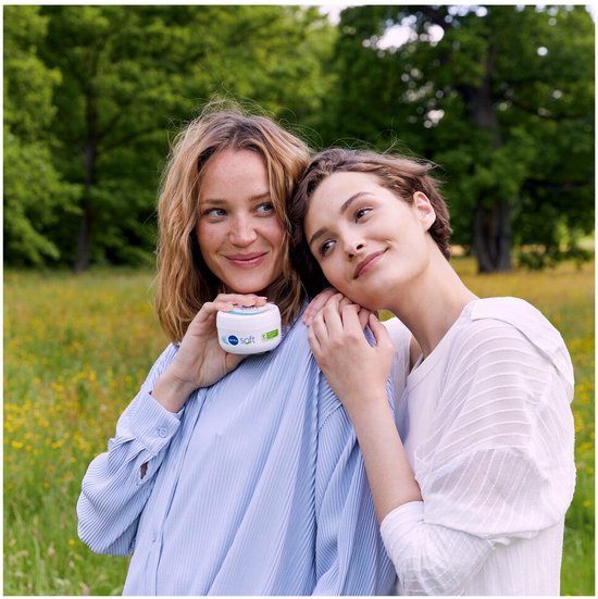 Twee vrouwen met blonde en bruine haren, glimlachend, met NIVEA Soft crème pot in een veld.