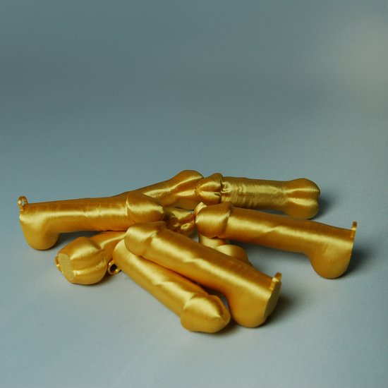 Een hoopje van zeven gouden, glimmende piemel kersthangers.