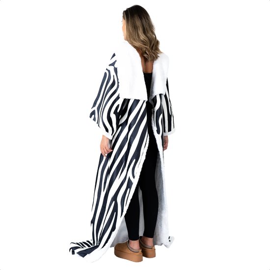Vrouw van achteren gezien, staand, gekleed in een lange zebra-print deken met mouwen en witte fleece voering.