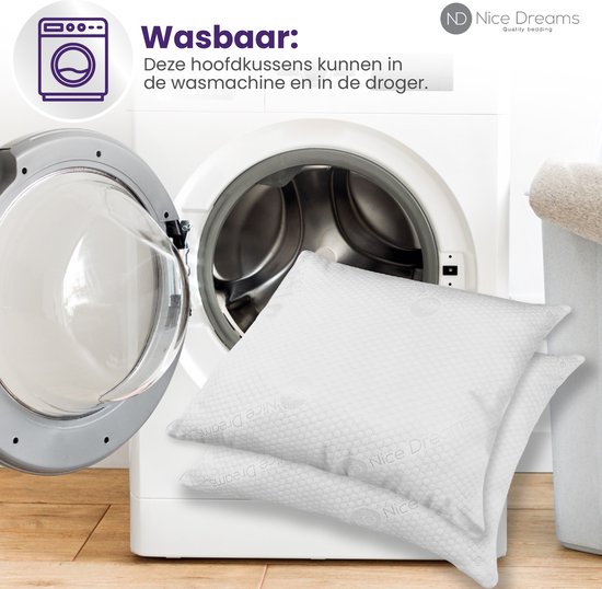 Twee witte kussens met hexagonaal patroon naast een geopende wasmachine. "Wasbaar: Deze hoofdkussens kunnen in de wasmachine en in de droger." is zichtbaar.