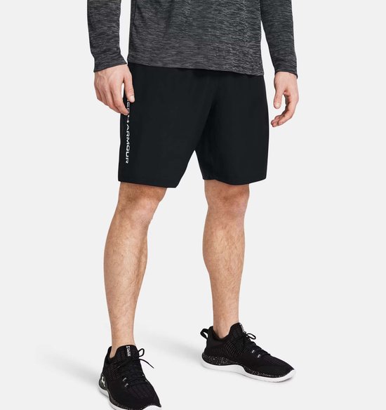 Man in zwart sportshirt met halve rits en zwart sportbroekje met logo op linkerbeen.