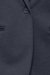 Detailopname van een marineblauwe blazer met een knoop en opgestikte zakken.