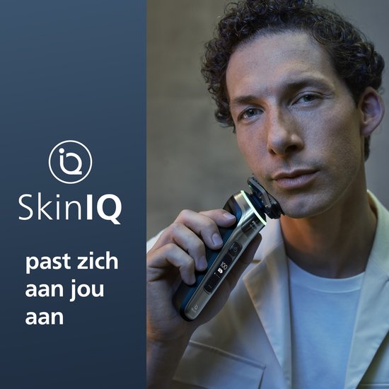 Un homme aux cheveux bouclés tient le rasoir Philips Series 9000 devant son visage.