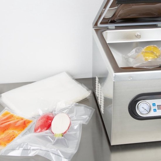 Roestvrijstalen vacuümmachine met open deksel, met een gele appel en groenten in vacuümzakken.