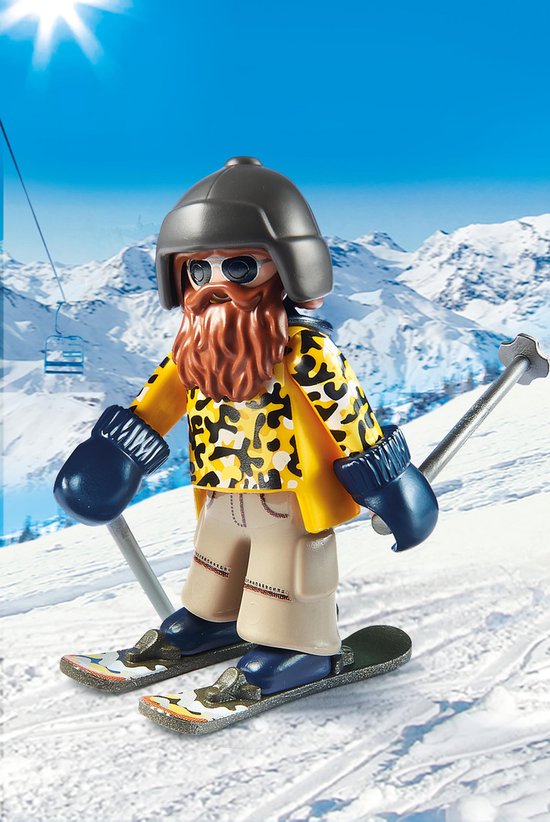 Playmobil skiër met baard, skibril, gele jas met luipaardprint, beige broek en blauwe wanten, op ski's in sneeuwlandschap.