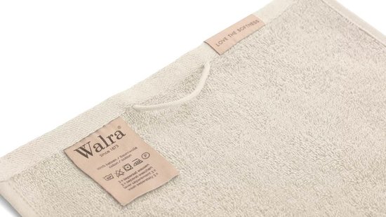 Detail van Walra waslabel en ophanglus op een crèmekleurige handdoek.