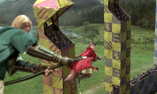 Harry Potter op een bezemsteel tijdens een Quidditch-wedstrijd in een stadion.