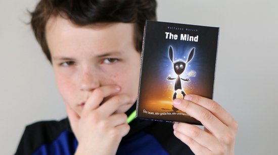 Jongen houdt de doos van 'The Mind' vast.