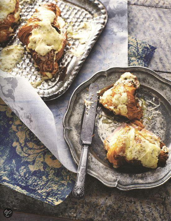 Croissants met kaas op zilveren borden.