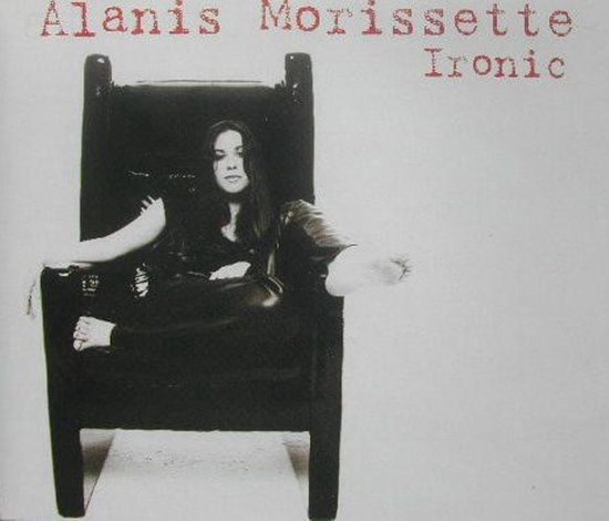 Alanis Morissette zit in een grote, donkere stoel. Ze draagt een zwarte outfit. De tekst "Alanis Morissette Ironic" staat erboven.