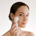 Een vrouw gebruikt de witte Braun FaceSpa Pro met opzetborstel op haar wang.